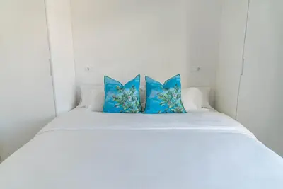 a white bed with two blue pillows on it at Morar Ourense in Ourense