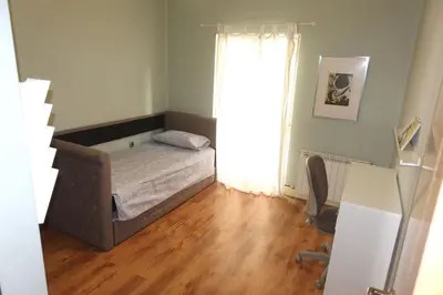 a small bedroom with a bed and a wooden floor at Antolín Yellow Door in Ponferrada
