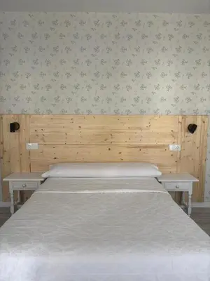a bed in a bedroom with a wooden wall at Hostal Quiper in Quiroga