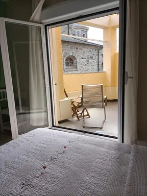 a bedroom with a window and a chair on a balcony at Hostal Quiper in Quiroga