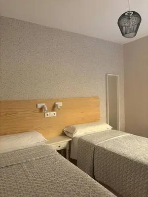 a hotel room with two beds and a desk at Hostal Quiper in Quiroga