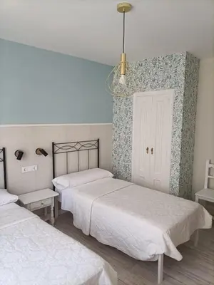 a bedroom with two beds and a chandelier at Hostal Quiper in Quiroga