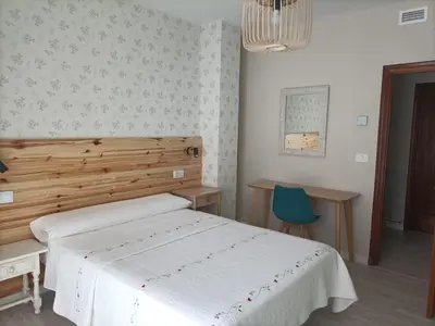 a bedroom with a white bed and a blue chair at Hostal Quiper in Quiroga