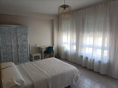 a bedroom with a bed and a table and a chandelier at Hostal Quiper in Quiroga