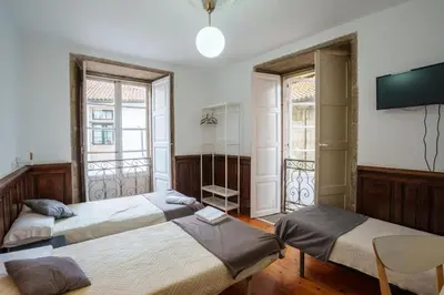 a bedroom with two beds and a tv on the wall at Hostal San Pelayo in Santiago de Compostela