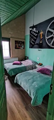 a bedroom with two beds and a painting on the wall at ALBERGUE peregrinos CASAFLOR in Murias de Rechivaldo