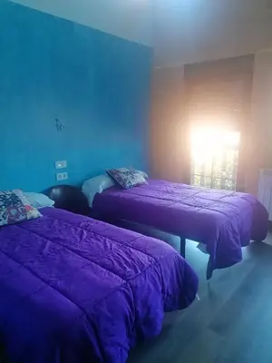 two beds in a room with purple sheets at ALBERGUE peregrinos CASAFLOR in Murias de Rechivaldo