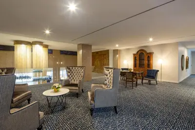 a lobby with chairs and a table and a dining room at Eurostars Gran Hotel Lugo in Lugo