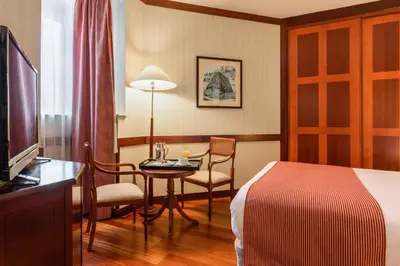 a hotel room with a bed and a table and a room at Eurostars Gran Hotel Santiago in Santiago de Compostela