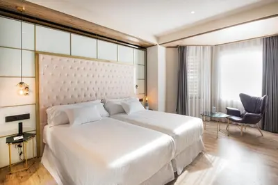 a bedroom with a large white bed and a chair at Barceló Ourense in Ourense