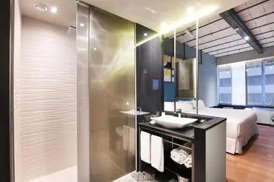 a bathroom with a sink and a bed and a mirror at Barceló Ourense in Ourense