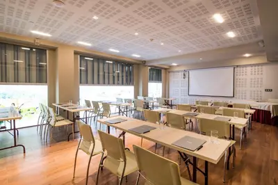 a classroom with tables and chairs and a projection screen at Barceló Ourense in Ourense
