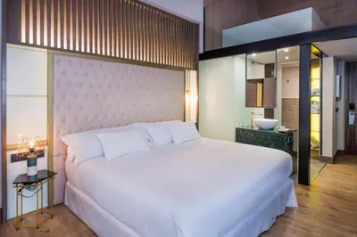 a bedroom with a large white bed and a bathroom at Barceló Ourense in Ourense