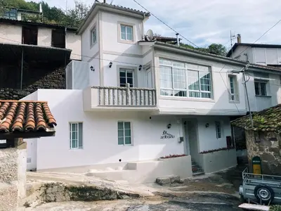 a white house with a balcony on top of it at Casa Amodiño in Belesar