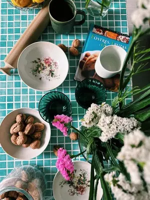 a table with plates of food and flowers and a book at Amodiño do Camiño in Belesar