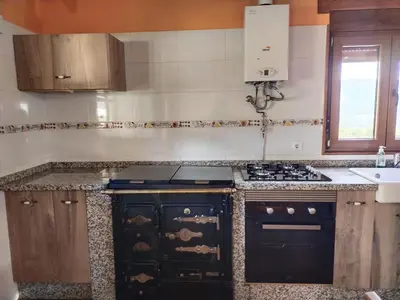 a kitchen with a black stove and a sink at Casa Antonio in Susañe del Sil