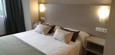 a bedroom with a bed with white sheets and pillows at Duerming Villa De Sarria Hotel in Sarria