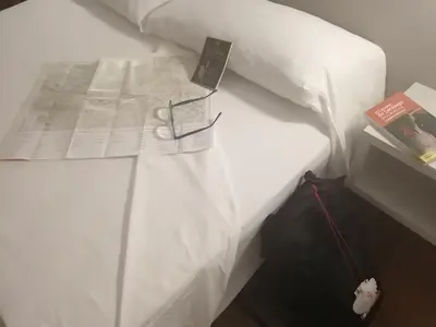 a bed with a book and a cell phone on it at Duerming Villa De Sarria Hotel in Sarria