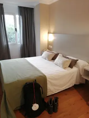 a hotel room with a bed with a bag on the floor at Duerming Villa De Sarria Hotel in Sarria