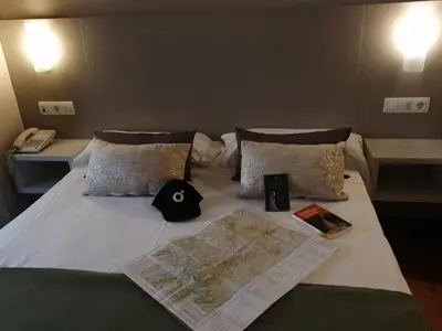 a bed with a map and a hat on it at Duerming Villa De Sarria Hotel in Sarria
