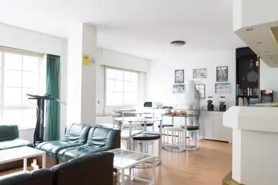 a living room with blue chairs and a kitchen at Rey Fernando in Santiago de Compostela