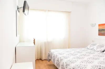 a white bedroom with a bed and a window at Rey Fernando in Santiago de Compostela