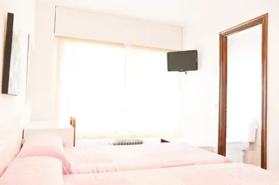 a white bedroom with two beds and a mirror at Rey Fernando in Santiago de Compostela