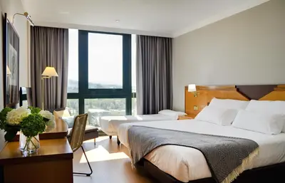 a hotel room with two beds and a desk at Oca Puerta del Camino Hotel in Santiago de Compostela