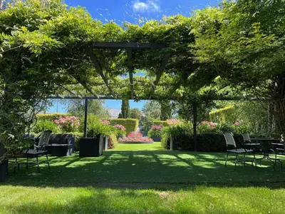 a pergola with chairs and tables in a garden at Oca Puerta del Camino Hotel in Santiago de Compostela
