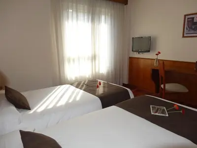 a hotel room with two beds and a television at Hotel El Pescador in Perillo
