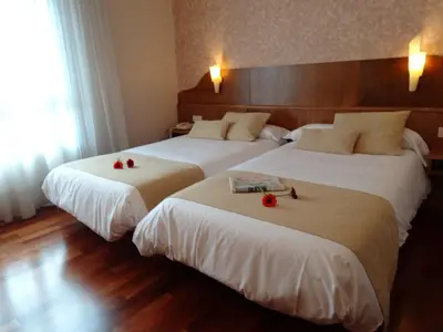 two beds in a hotel room with red roses on them at Hotel El Pescador in Perillo