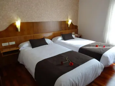 a hotel room with three beds with red cherries on them at Hotel El Pescador in Perillo