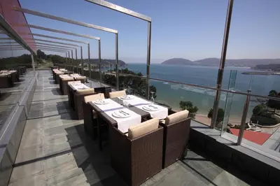 a row of tables on a balcony with a view of the ocean at Apartamentos Las Sirenas in Viveiro
