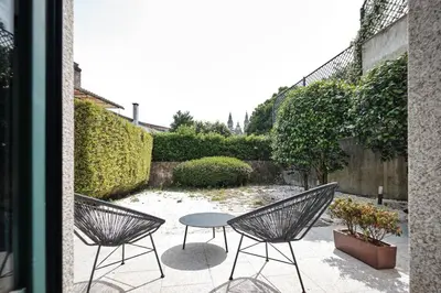 a patio with two chairs and a table in a garden at Hotel Pombal Rooms in Santiago de Compostela