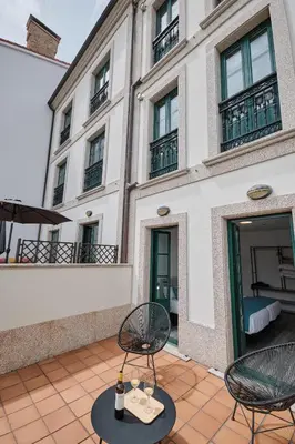 a patio with chairs and tables in front of a building at Hotel Pombal Rooms in Santiago de Compostela