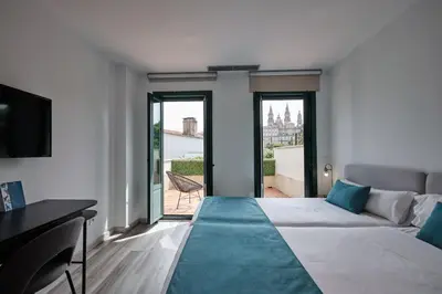 a bedroom with a large bed with a large window at Hotel Pombal Rooms in Santiago de Compostela