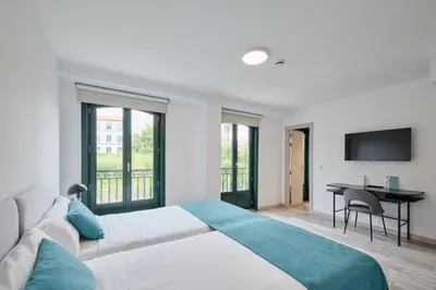 a bedroom with a bed and a desk with a television at Hotel Pombal Rooms in Santiago de Compostela