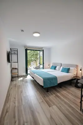 a bedroom with a large bed and wooden floors at Hotel Pombal Rooms in Santiago de Compostela