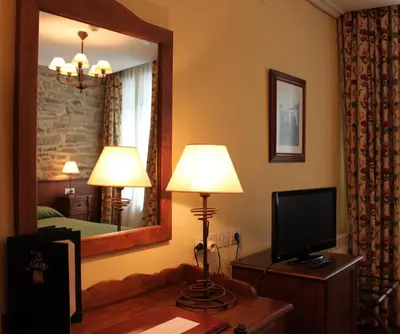 a living room with a television and a mirror at San Clemente by Pousadas de Compostela in Santiago de Compostela