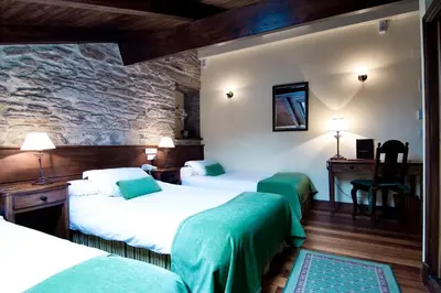 a hotel room with three beds and a stone wall at San Clemente by Pousadas de Compostela in Santiago de Compostela