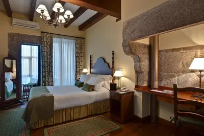 a bedroom with a bed and a mirror and a desk at Airas Nunes by Pousadas de Compostela in Santiago de Compostela