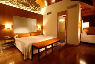 a bedroom with a bed and a bench in it at Hotel Altaïr in Santiago de Compostela