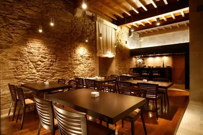 a restaurant with tables and chairs and a stone wall at Hotel Altaïr in Santiago de Compostela