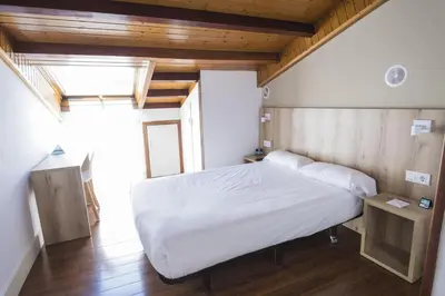 a bedroom with a white bed and a wooden ceiling at Hotel Alda Avenida in Santiago de Compostela