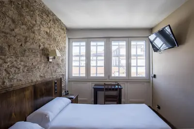 a bedroom with a bed and a tv on the wall at Hotel Alda Avenida in Santiago de Compostela