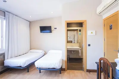 a hospital room with two beds and a mirror at Hotel Alda Avenida in Santiago de Compostela