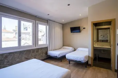 a hotel room with two beds and a window at Hotel Alda Avenida in Santiago de Compostela