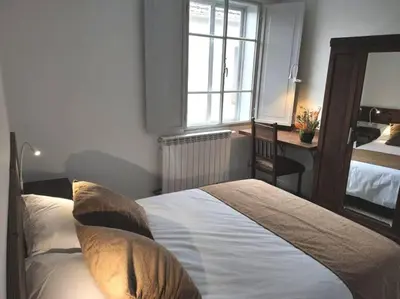 a bedroom with a bed with pillows and a desk at Casa Carmiña: Casa para pequeños grupos en el corazón de Galicia in O Irixo