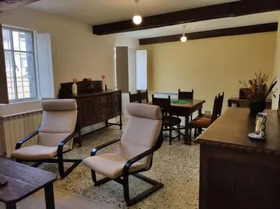 a living room with chairs and a table and a piano at Casa Carmiña: Casa para pequeños grupos en el corazón de Galicia in O Irixo