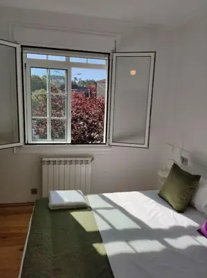 a bedroom with a large bed with two windows at Casa Carmiña: Casa para pequeños grupos en el corazón de Galicia in O Irixo